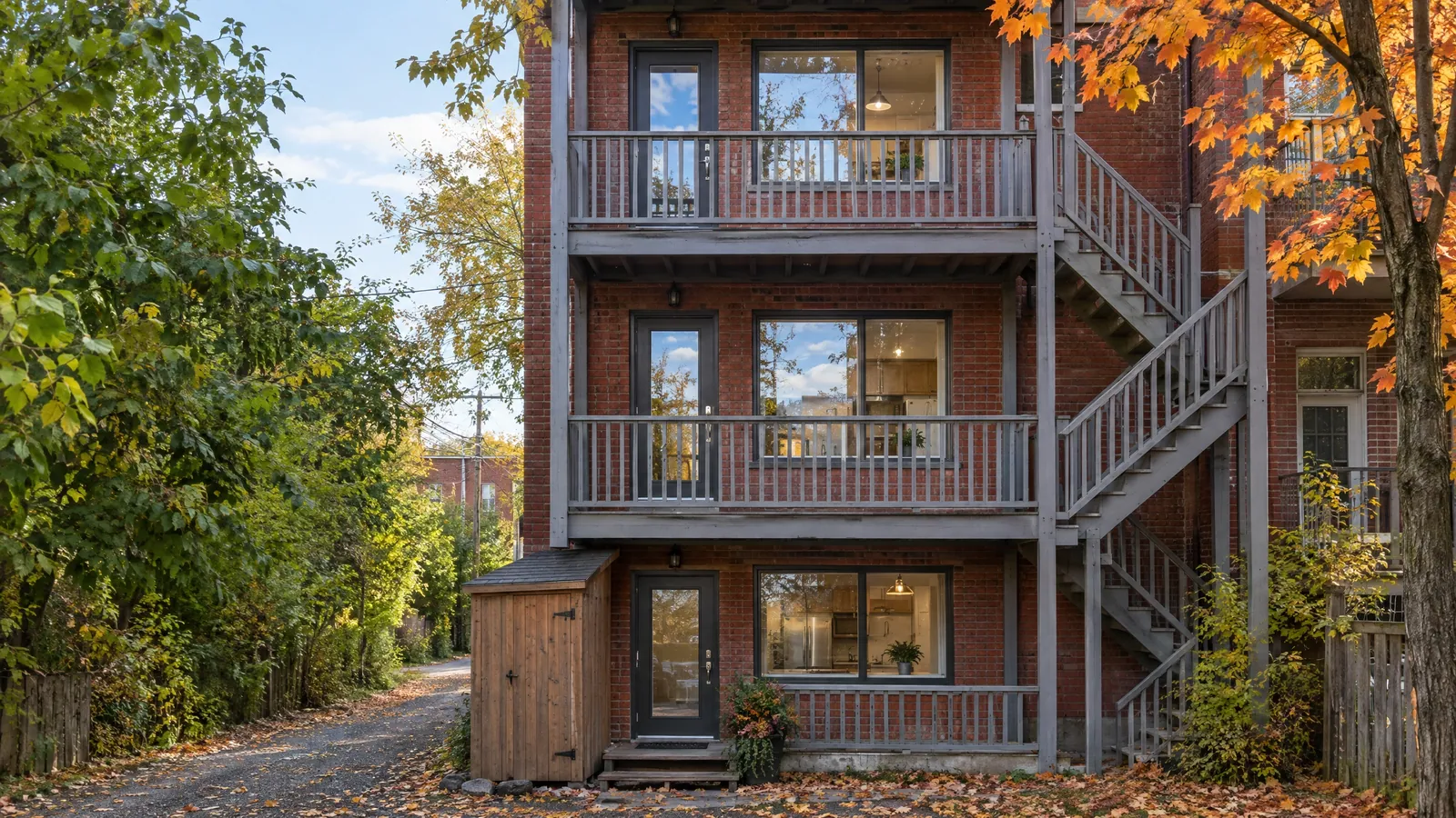 Back of a triplex with stacked galleries and a glass door opening onto each floor's balcony