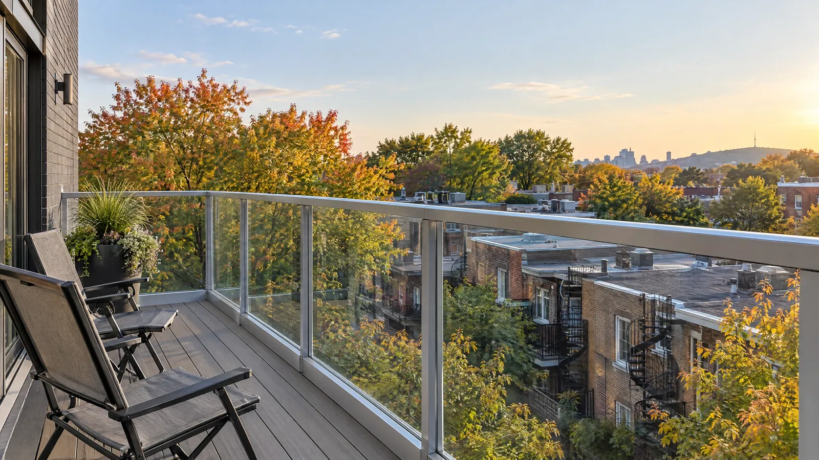 Upper balcony with glass panels between aluminum posts, overlooking plex rooftops and spiral staircases in autumn