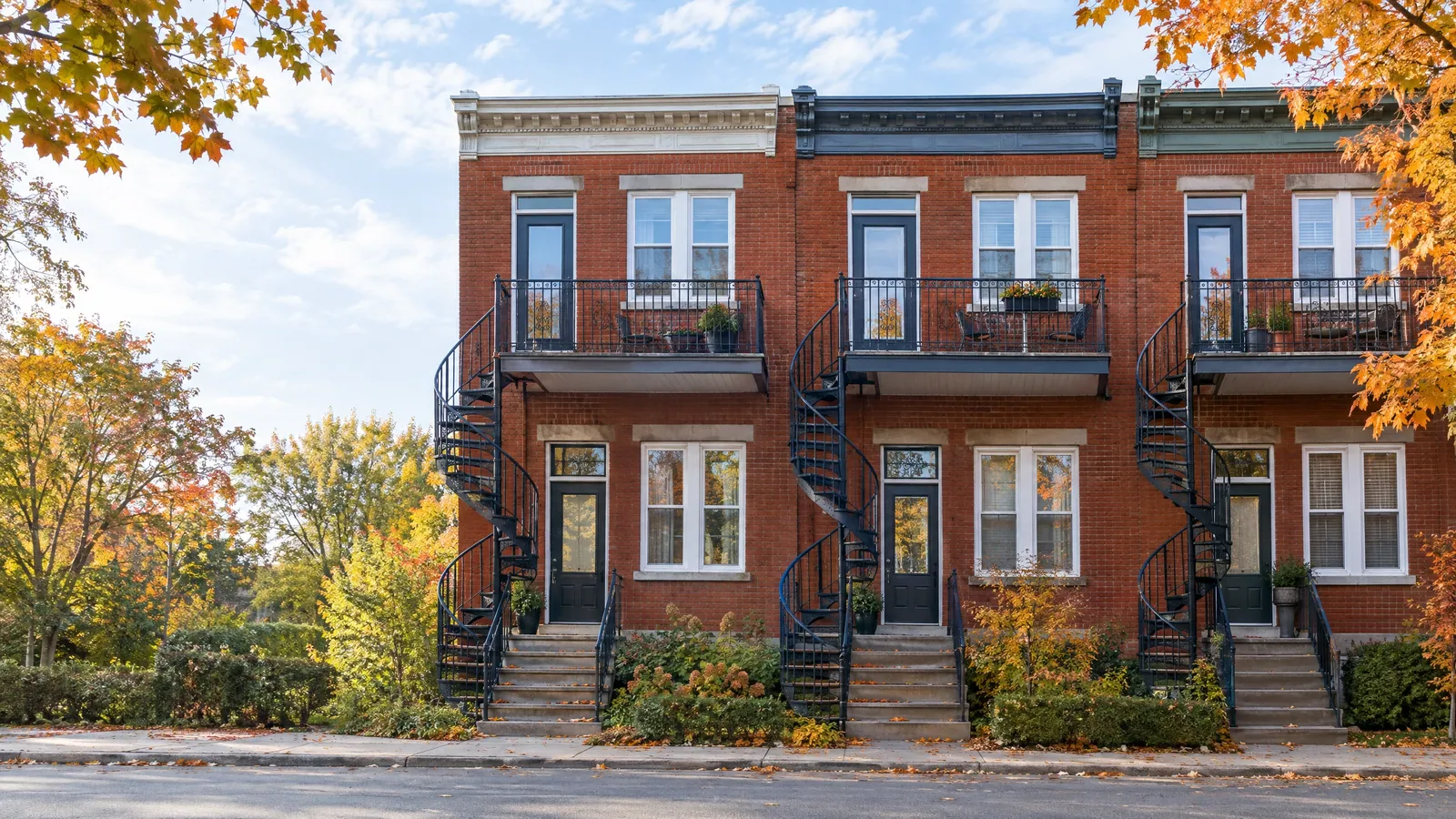 Row of brick triplexes with spiral outdoor staircases climbing to a glazed balcony door on each floor